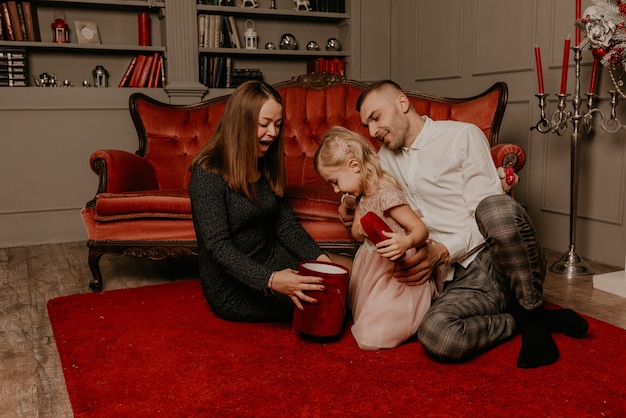 Famiglia felice con bambino che celebra il nuovo anno e il Natale all'albero di Natale decorato e alle ghirlande