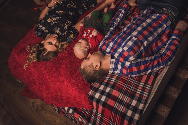 Famiglia felice con bambino che celebra il nuovo anno e il Natale all'albero di Natale decorato e alle ghirlande