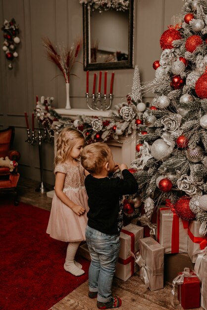 Famiglia felice con bambino che celebra il nuovo anno e il Natale all'albero di Natale decorato e alle ghirlande