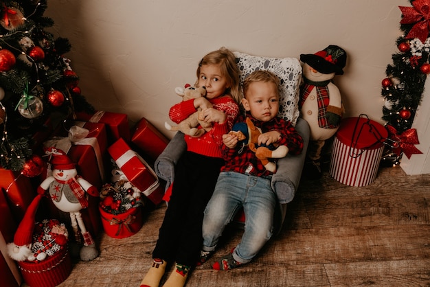 Famiglia felice con bambino che celebra il nuovo anno e il Natale all'albero di Natale decorato e alle ghirlande