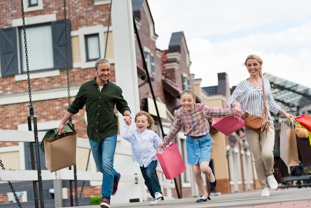 Famiglia felice con borse della spesa che si tengono per mano e camminano durante lo shopping