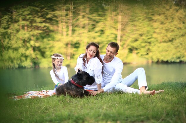 Famiglia felice con cane al picnic in una soleggiata giornata estiva incinta