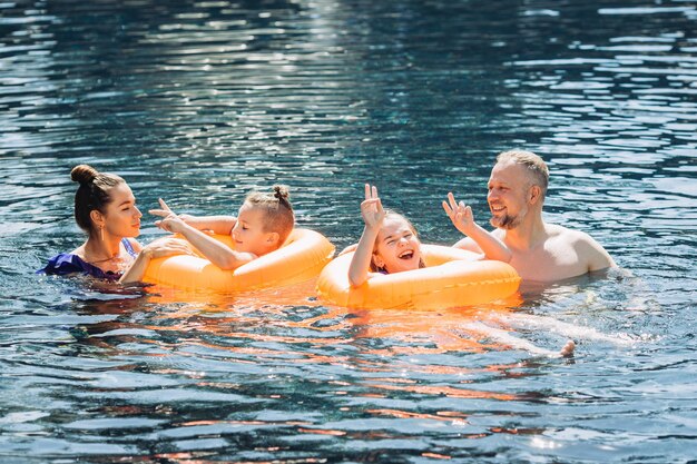 Famiglia felice con due bambini che si divertono in piscina Concetto di vacanza estiva