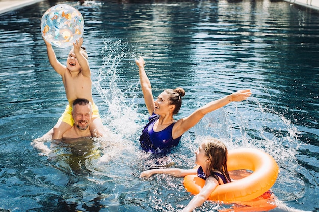 Famiglia felice con due bambini che si divertono in piscina Concetto di vacanza estiva