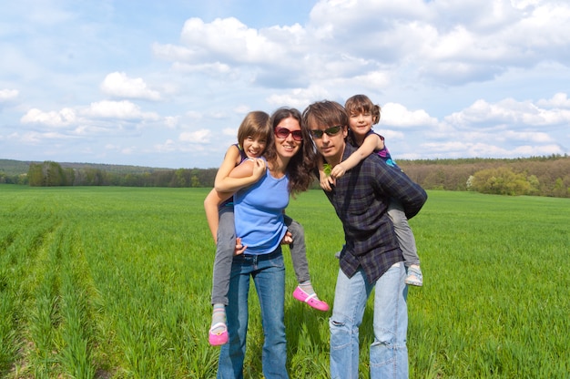 Famiglia felice con due bambini sul campo verde