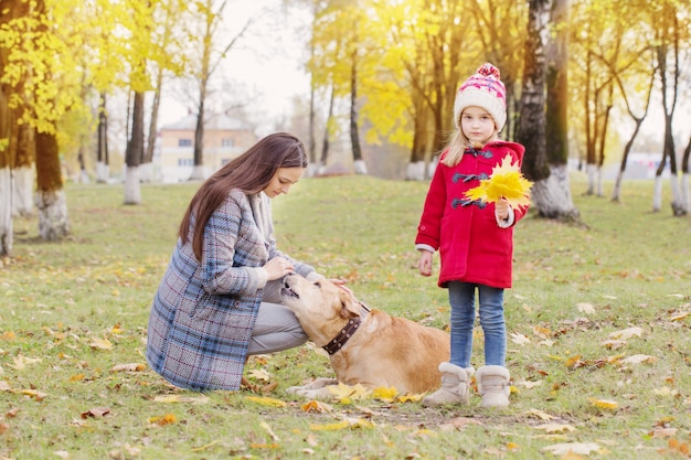 Famiglia felice con il cane nel soleggiato parco autunnale