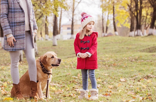 Famiglia felice con il cane nella soleggiata sosta di autunno