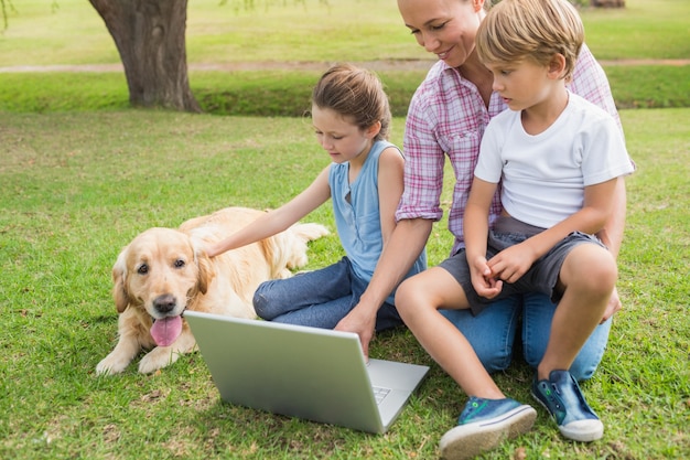 Famiglia felice con il loro cane usando il portatile