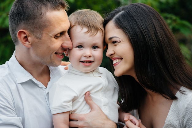 Famiglia felice con il loro figlio che cammina nel parco al tramonto. Felicità. Amore