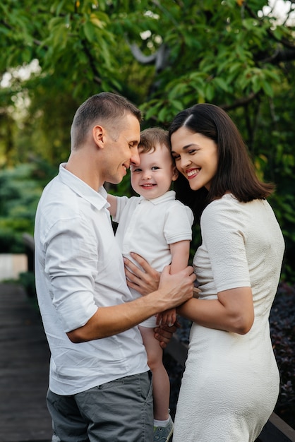 Famiglia felice con il loro figlio che cammina nel parco al tramonto. Felicità. Amore