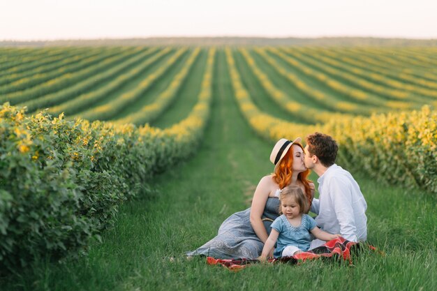 Famiglia felice con la piccola figlia che passa insieme tempo nel campo soleggiato