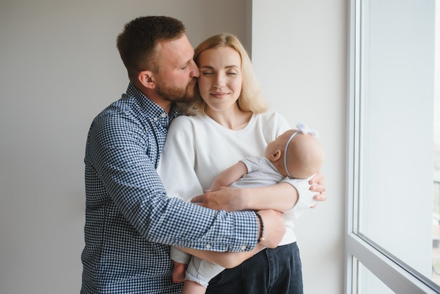 Famiglia felice con neonato vicino alla finestra