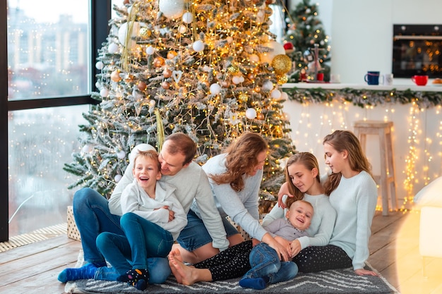 Famiglia felice con quattro fratelli germani vicino all'albero di Natale con le caselle presenti. Mattina in famiglia di Natale, concetto di umore natalizio