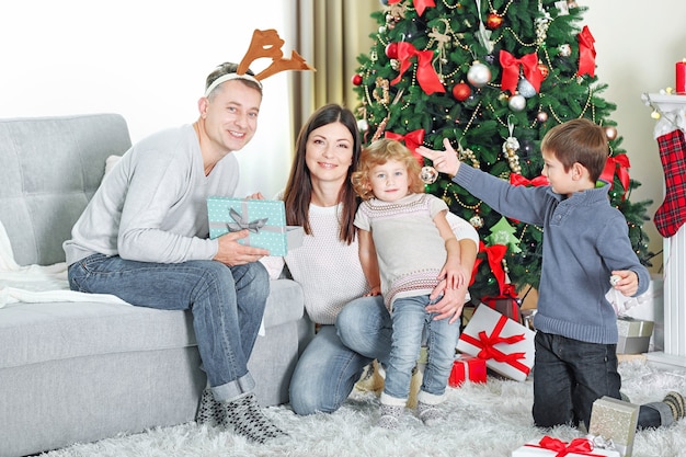 Famiglia felice con scatole regalo nel soggiorno delle vacanze di casa, al mattino