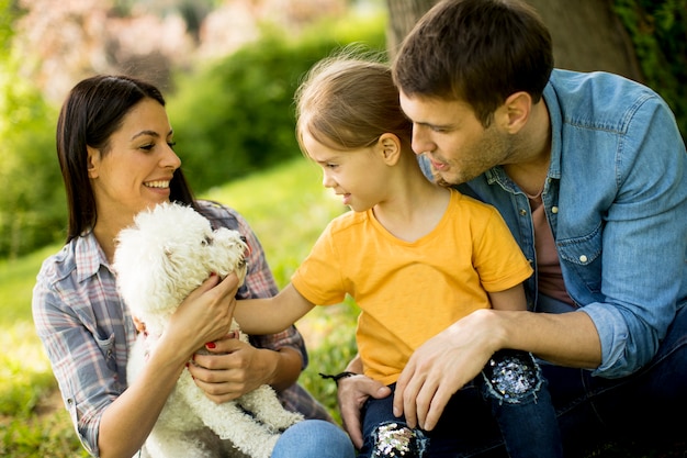 Famiglia felice con simpatico cane Bichon nel parco