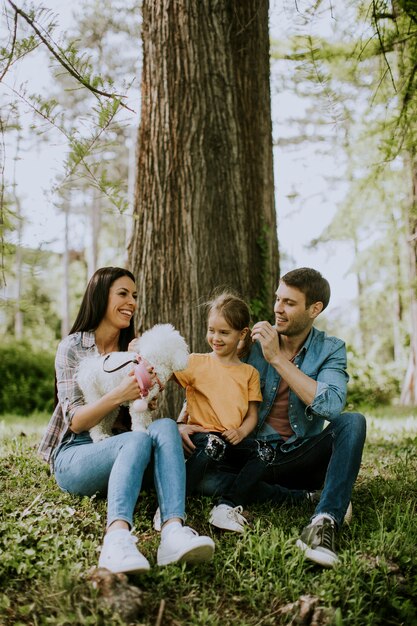 Famiglia felice con simpatico cane Bichon nel parco