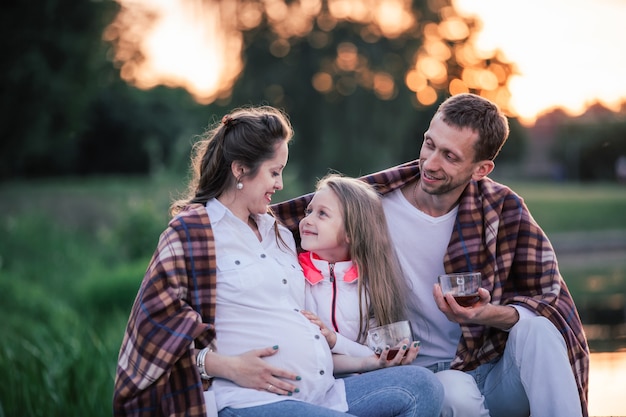 Famiglia felice con tazze di tè durante un picnic in una giornata fresca