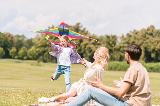 famiglia felice con un bambino che gioca con l'aquilone colorato nel parco