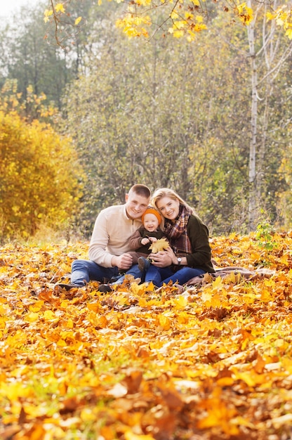 Famiglia felice con un bambino piccolo nella sosta di autunno