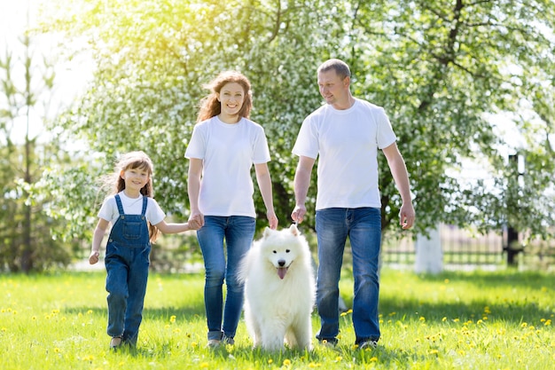 Famiglia felice con un cane bianco in un parco estivo.