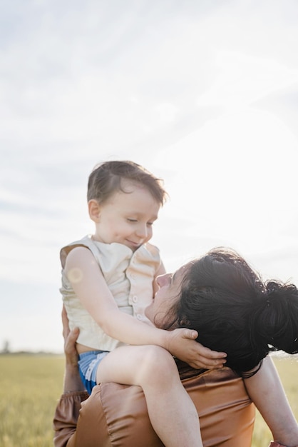 Famiglia felice della madre e del bambino che cammina sul campo di grano che abbraccia e che bacia