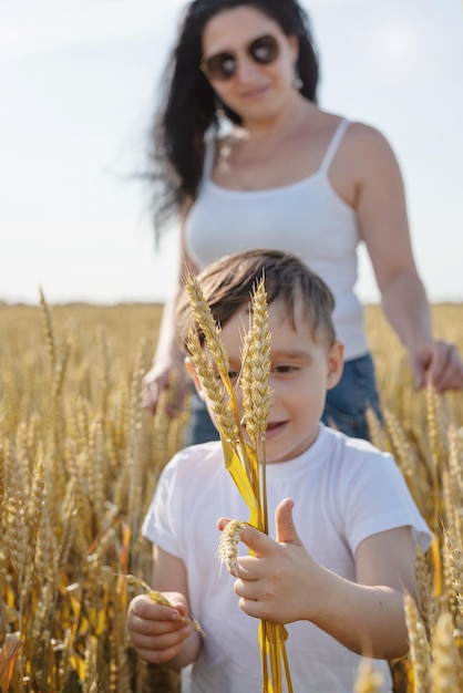 Famiglia felice della madre e del bambino neonato che cammina sul campo di grano
