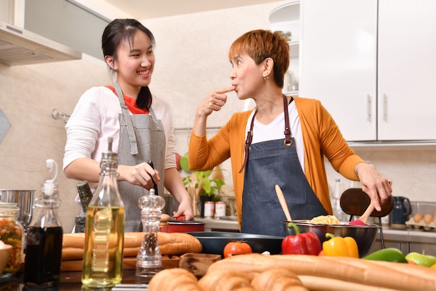 Famiglia felice della madre e della figlia che cucinano nella cucina che produce insieme alimento sano sentirsi divertimento