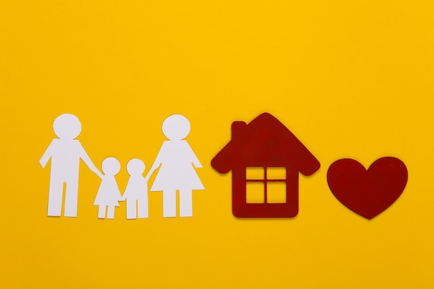 Famiglia felice di carta insieme a casa, cuore rosso su giallo