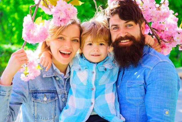 Famiglia felice di primavera nel giardino di sakura madre padre e figlio piccolo insieme nel parco fiorito