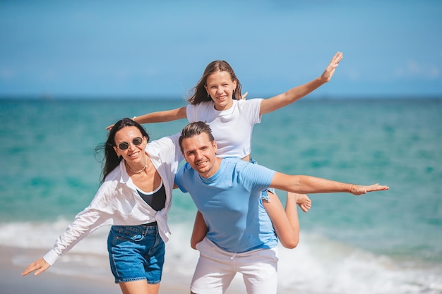 Famiglia felice di tre persone sulla spiaggia durante le vacanze estive