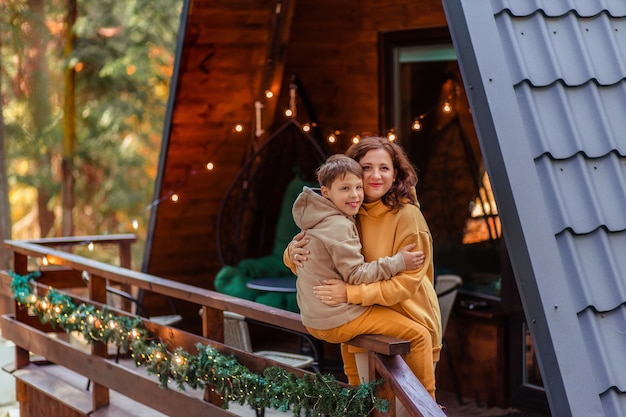 Famiglia felice di viaggiatori nella foresta in montagna vicino alla casa chalet in legno