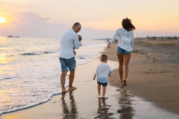 Famiglia felice divertendosi a giocare in spiaggia durante le vacanze estive sulla spiaggia Famiglia felice e concetto di vacanze Paesaggio marino al tramonto con bel cielo Famiglia sulla spiaggia