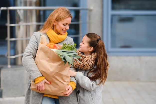 Famiglia felice dopo lo shopping con le borse della spesa sul parcheggio vicino al centro commerciale. madre con figlia.