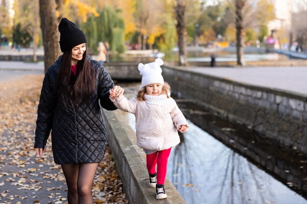 Famiglia felice durante una passeggiata autunnale Madre e figlia passeggiano nel parco e si godono insieme la bellissima natura autunnale