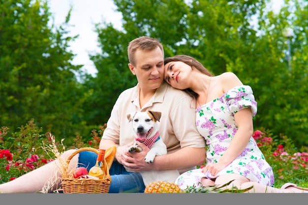 Famiglia felice giovane coppia in giardino a un picnic innamorato donna e uomo sull'erba con i loro d...
