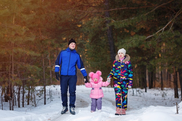 Famiglia felice, giovani coppie e la loro figlia trascorrere del tempo all'aperto in inverno