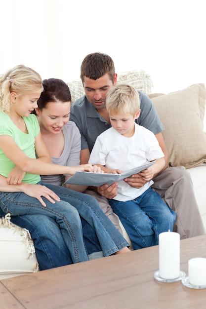 Famiglia felice guardando un album di foto seduti insieme nel soggiorno