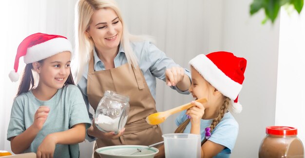 Famiglia felice in cucina. Madre e due piccole figlie che preparano l'impasto per i biscotti di Natale.