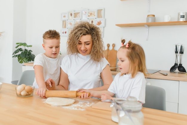 Famiglia felice in cucina. madre e figli preparano la pasta, cuociono i biscotti