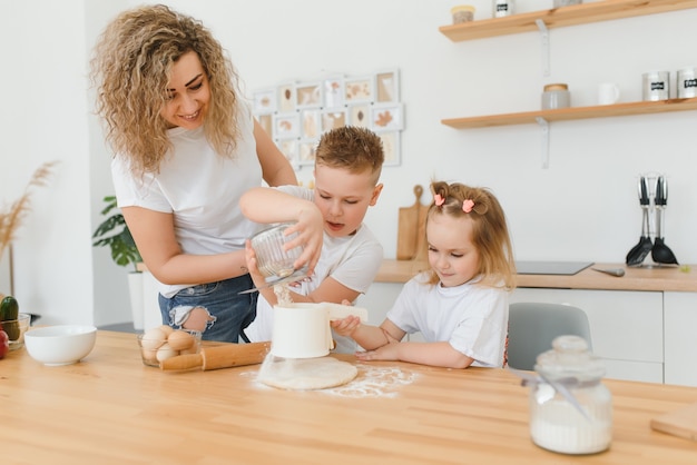 Famiglia felice in cucina. madre e figli preparano la pasta, cuociono i biscotti