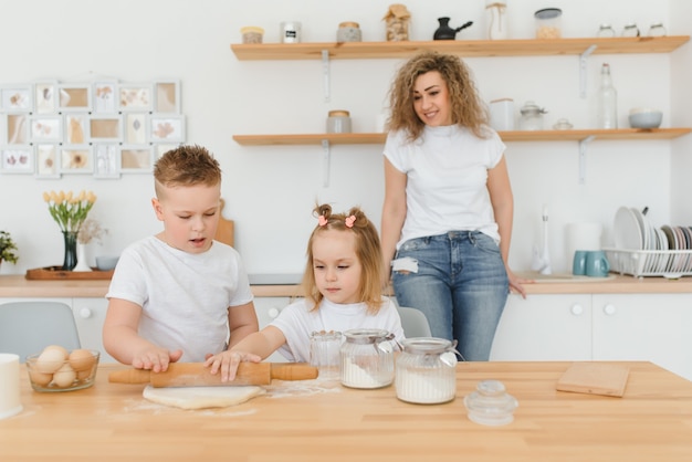 Famiglia felice in cucina. madre e figli preparano la pasta, cuociono i biscotti