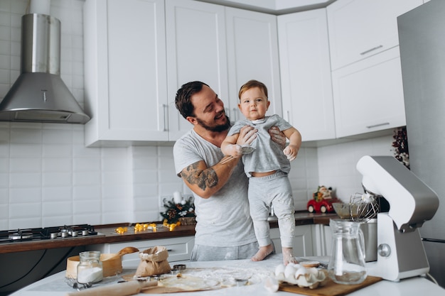 Famiglia felice in cucina. padre e figlio preparano l'impasto, cuociono i biscotti