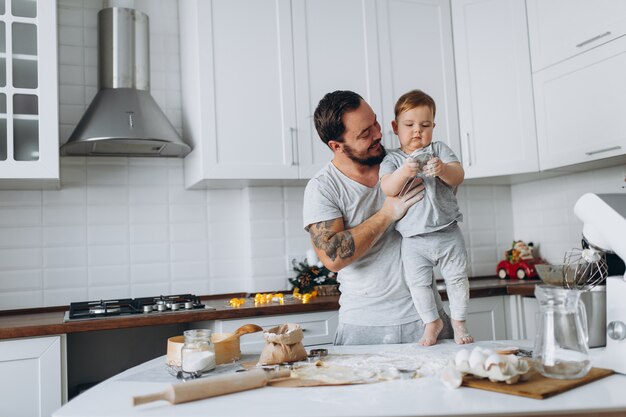 Famiglia felice in cucina. padre e figlio preparano l'impasto, cuociono i biscotti