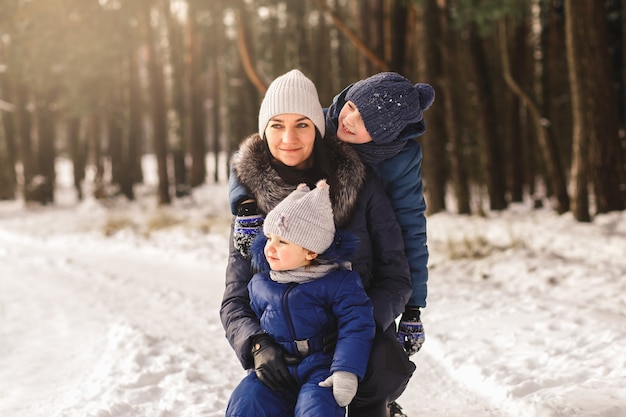 Famiglia felice in inverno in una passeggiata nel bosco. Mamma con bambini