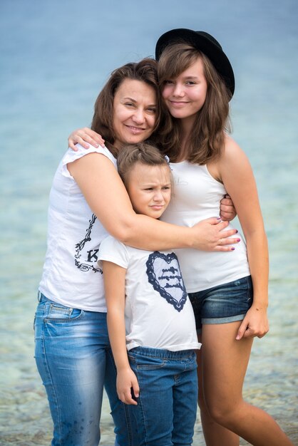 Famiglia felice in piedi su un pontile di legno di fronte al mare in estate