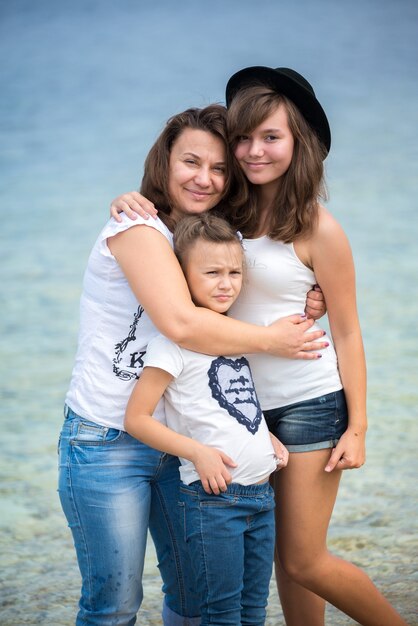 Famiglia felice in piedi su un pontile di legno di fronte al mare in estate