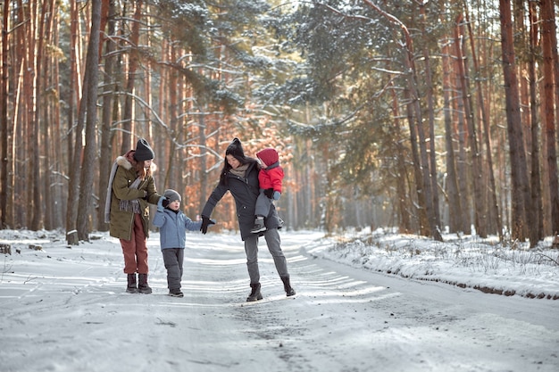 Famiglia felice in una passeggiata all'aperto nella soleggiata foresta invernale