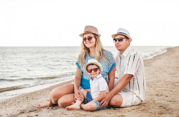 Famiglia felice in vacanza. Sulla spiaggia si trovano mamma, papà e un figlio piccolo. Famiglia in viaggio. Baci, sorrisi