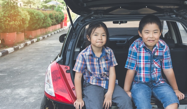 Famiglia felice in viaggio, seduti nel bagagliaio della macchina