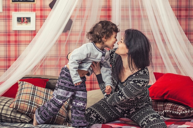 Famiglia felice madre e bambino insieme a casa delle camere da letto in interni invernali